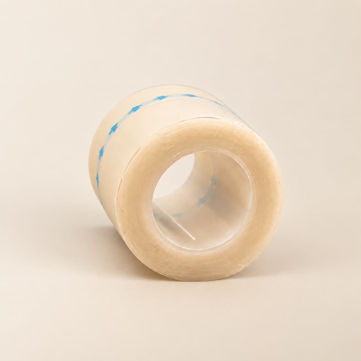 1 metre hydrocolloid tape roll with a clear core and blue arrows on the backing, on a cream background